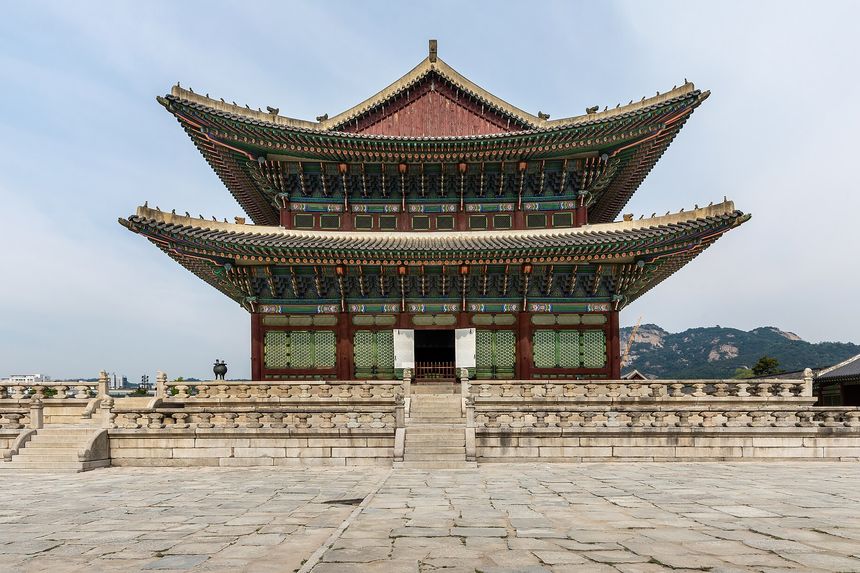 The main throne hall of Gyeongbokgung Palace, its bracketed double roof seen head-on across the stone courtyard.